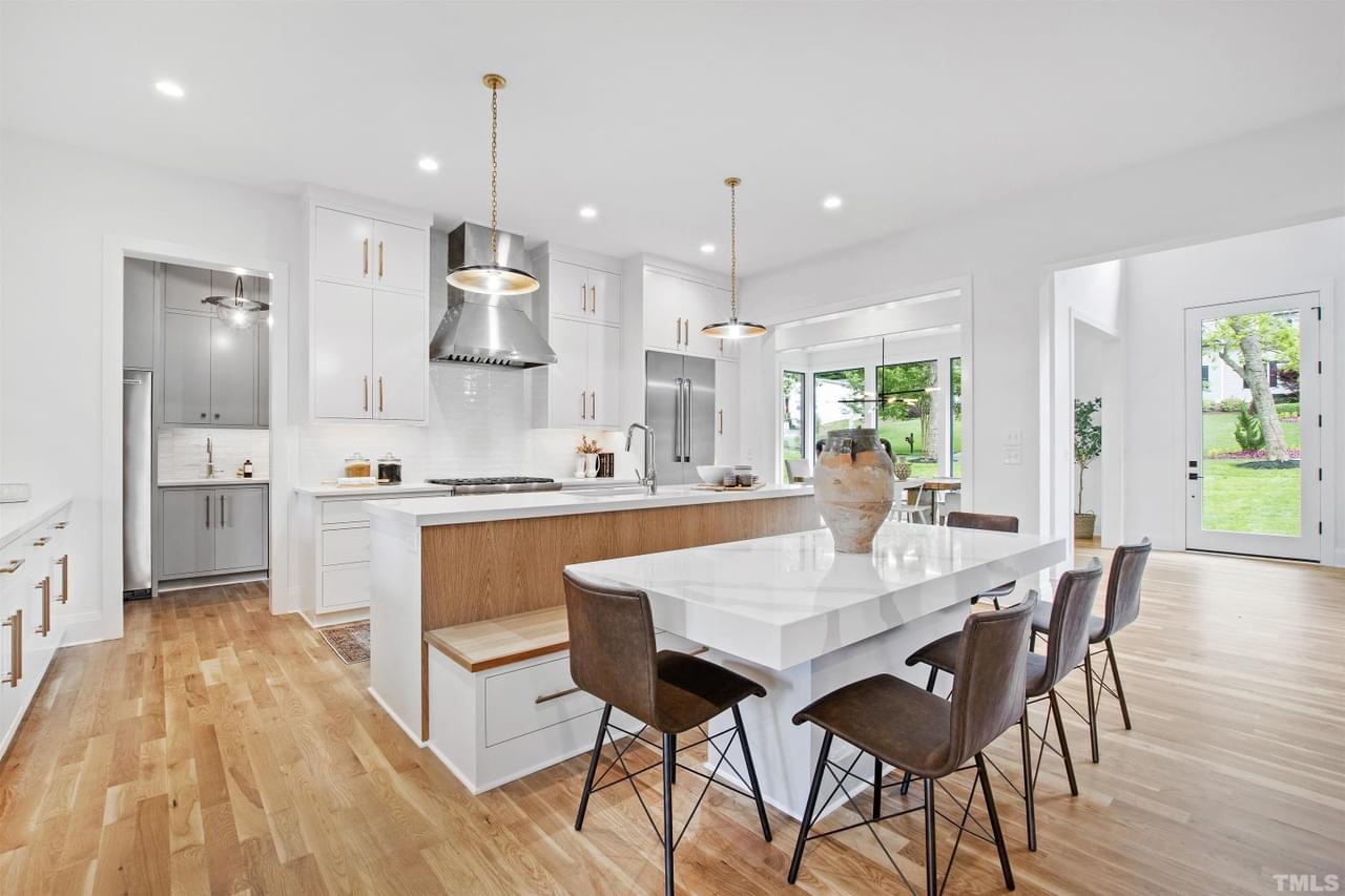 A sparkling white kitchen with wood floor, sharp angles, and clean lines